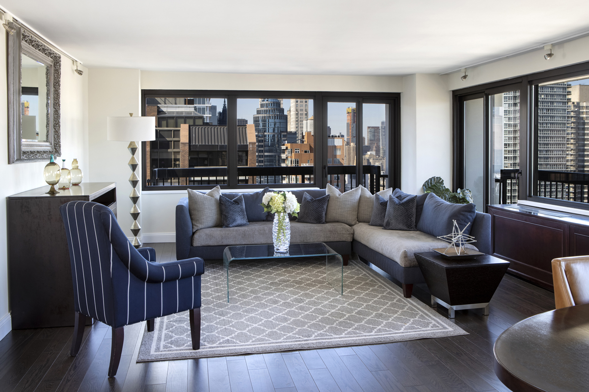 a living room with furniture potted plant kitchen view and a large window