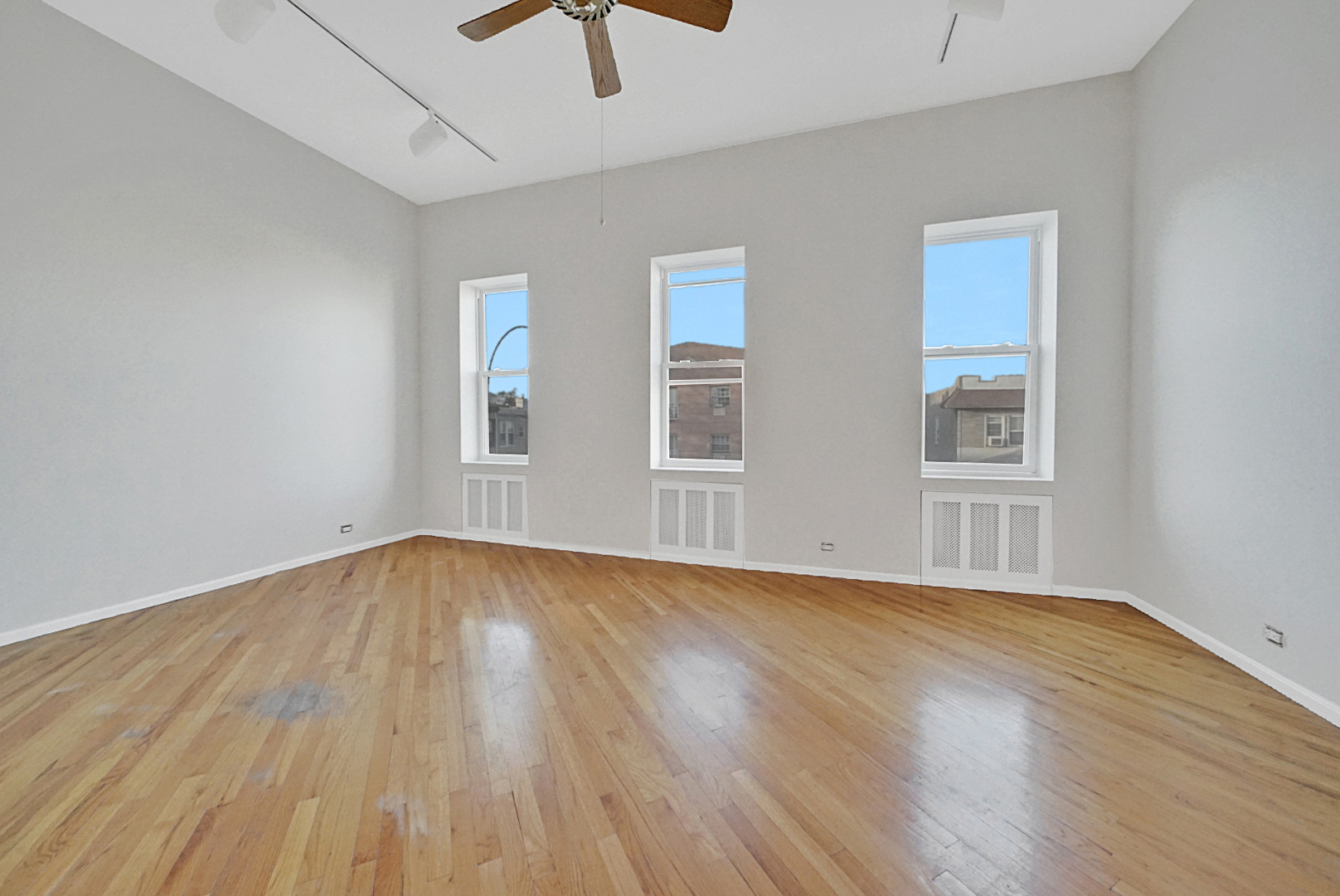 a view of an empty room with wooden floor and window