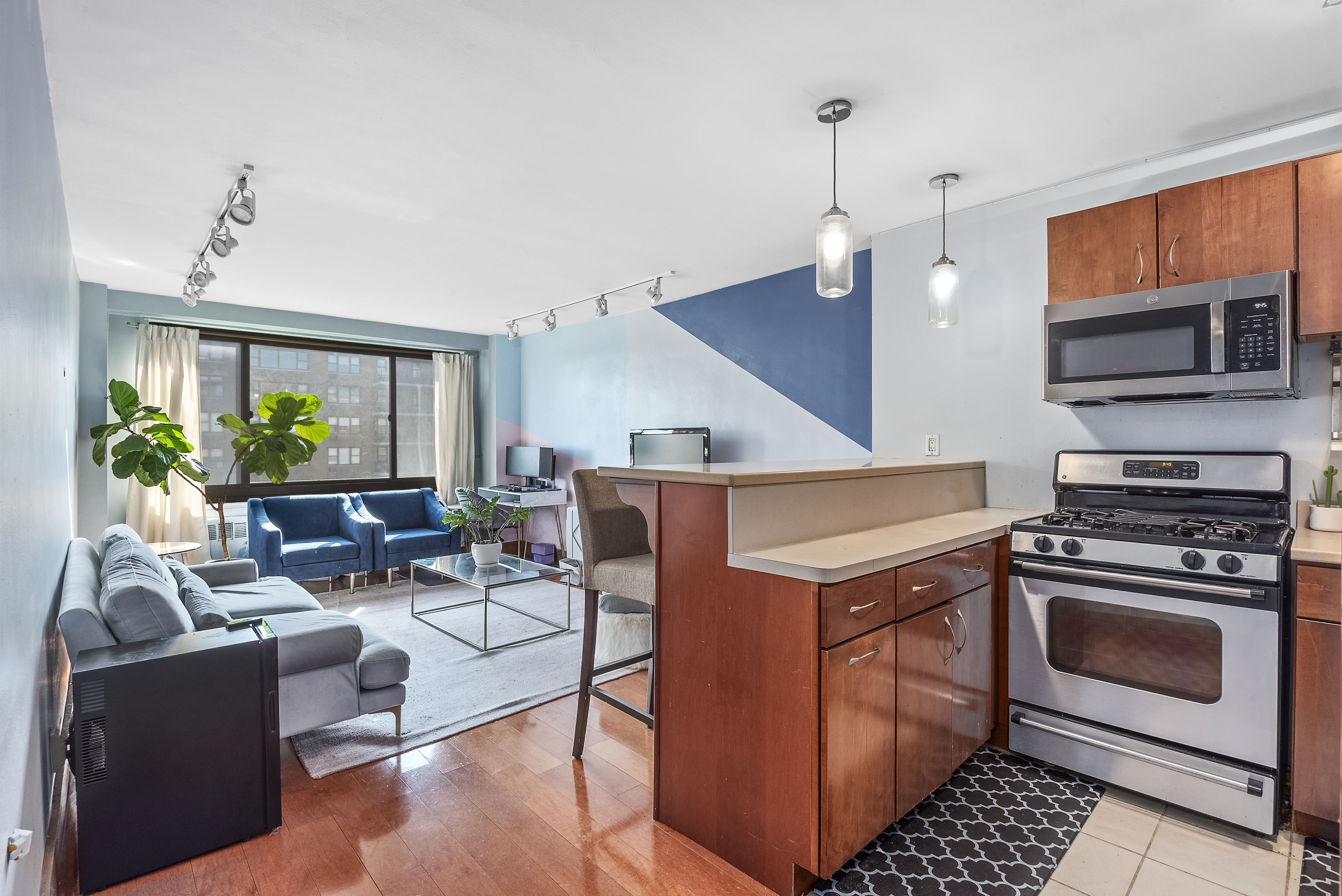 a living room with furniture a flat screen tv and kitchen view