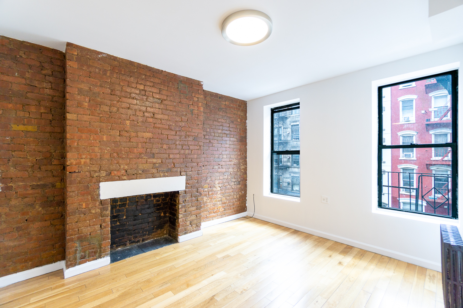 a view of an empty room with a fireplace and a window