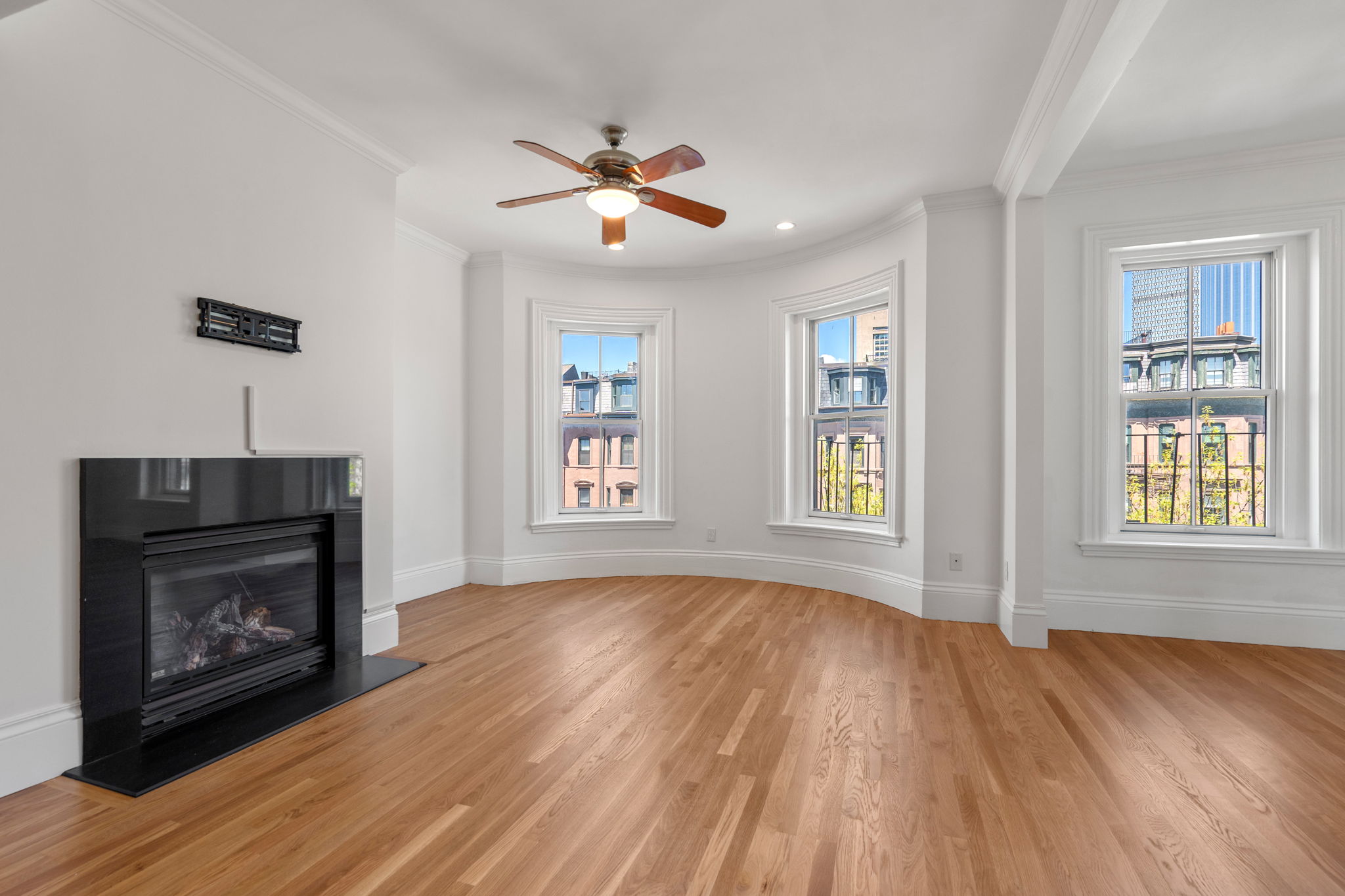 a view of an empty room with wooden floor fireplace and a window