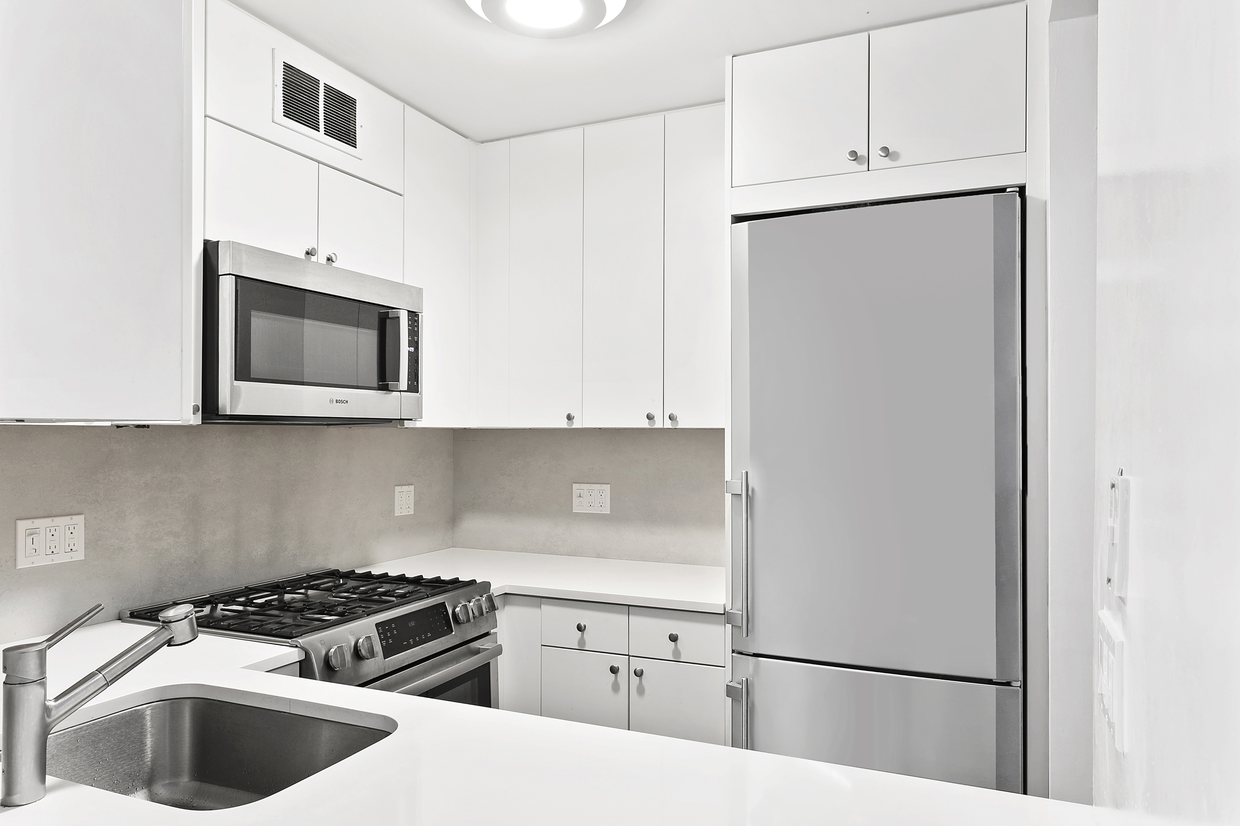 a kitchen with white cabinets and black appliances