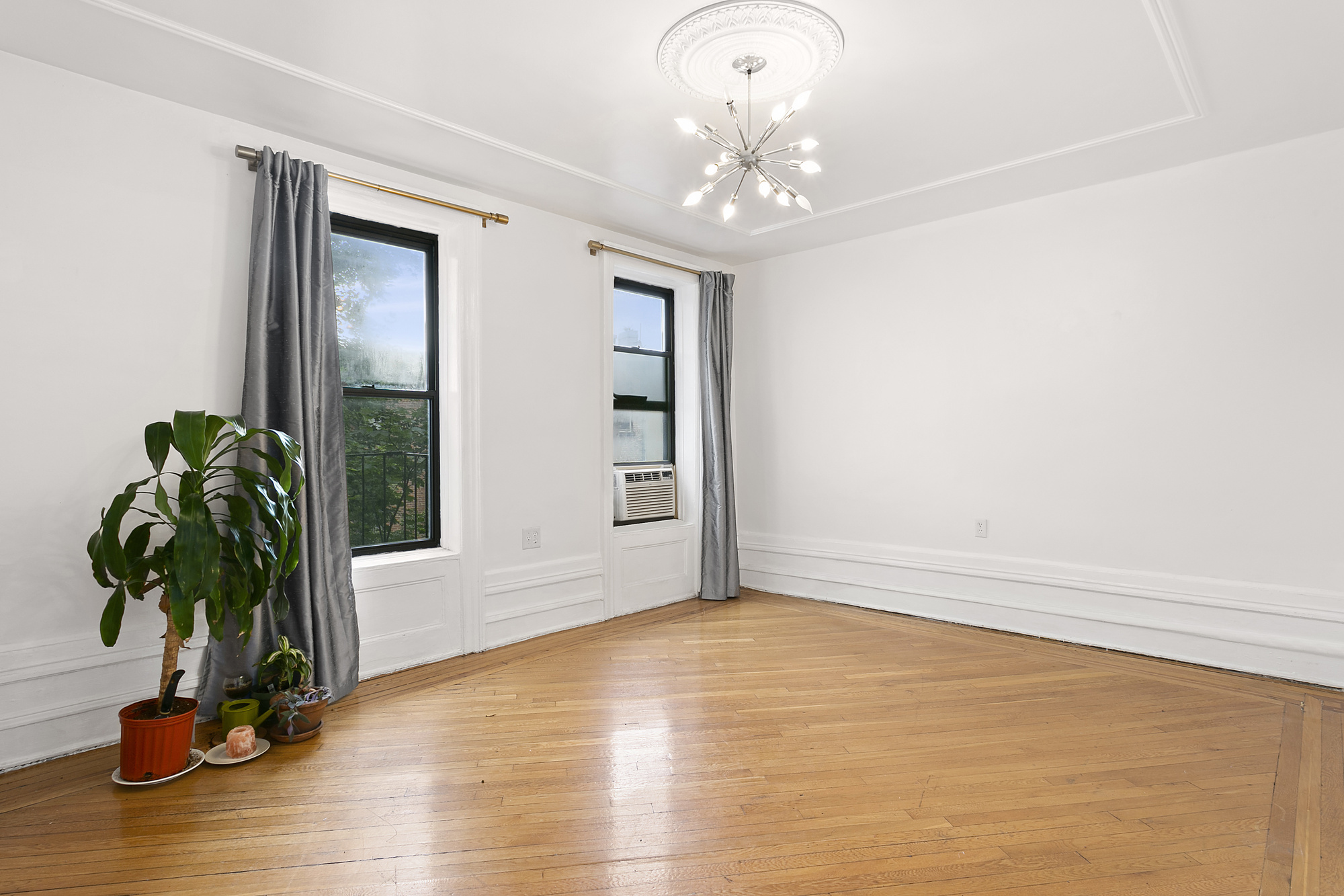 a view of an empty room with window and wooden floor