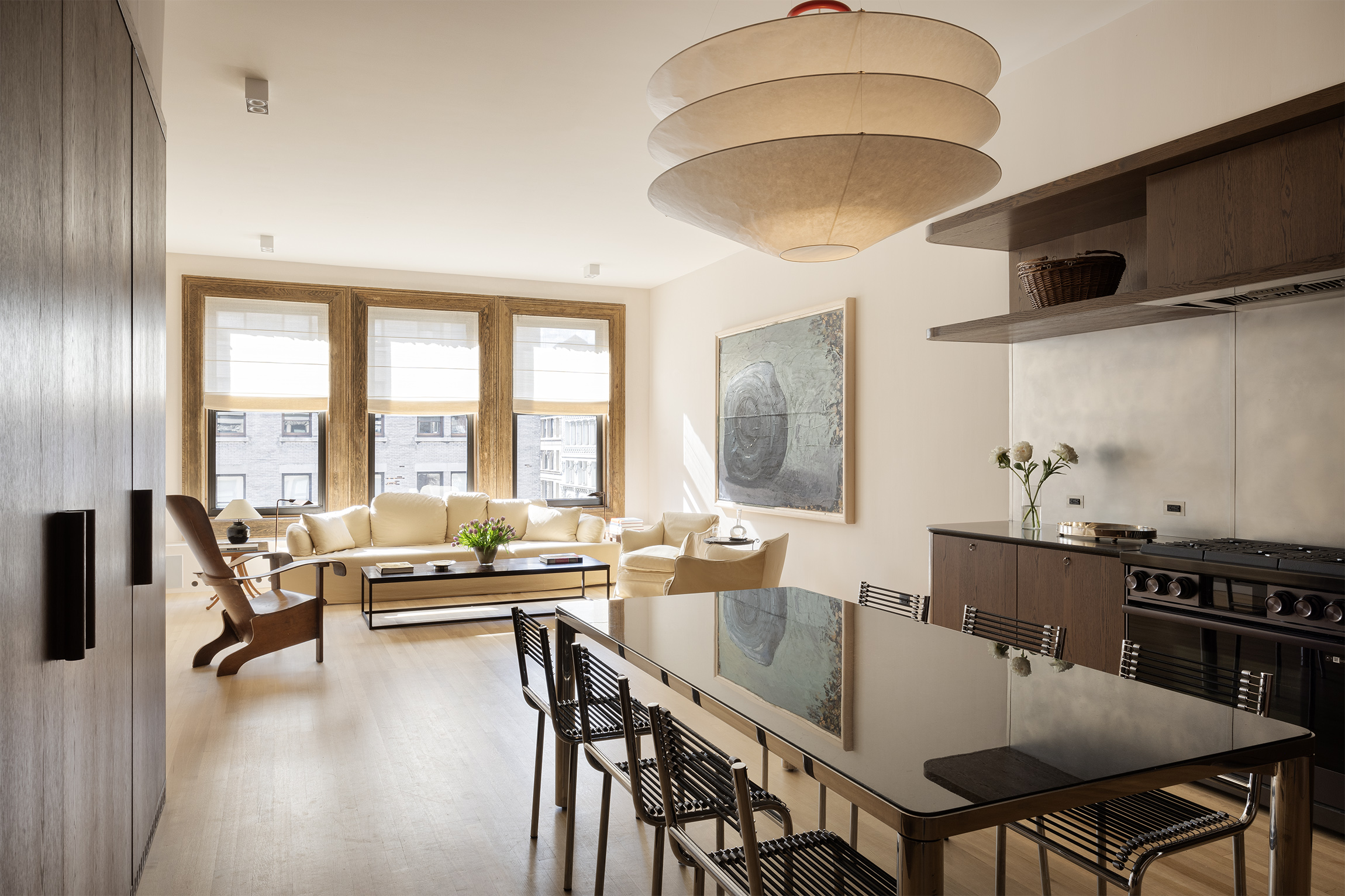 a dining room with stainless steel appliances furniture a large window and a kitchen view