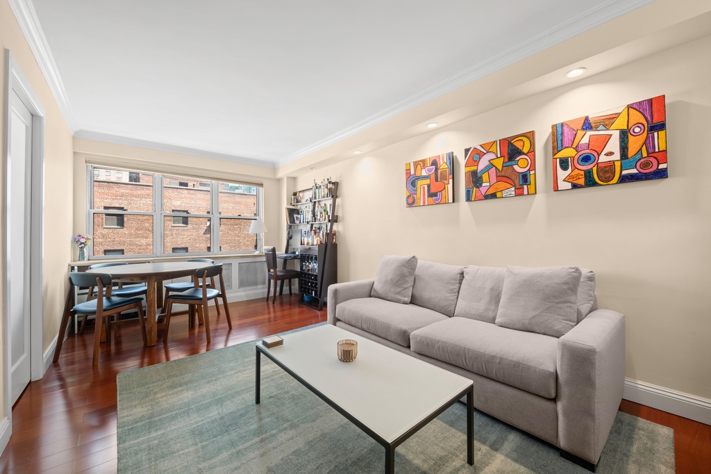 a living room with furniture a dining table with wooden floor and kitchen view