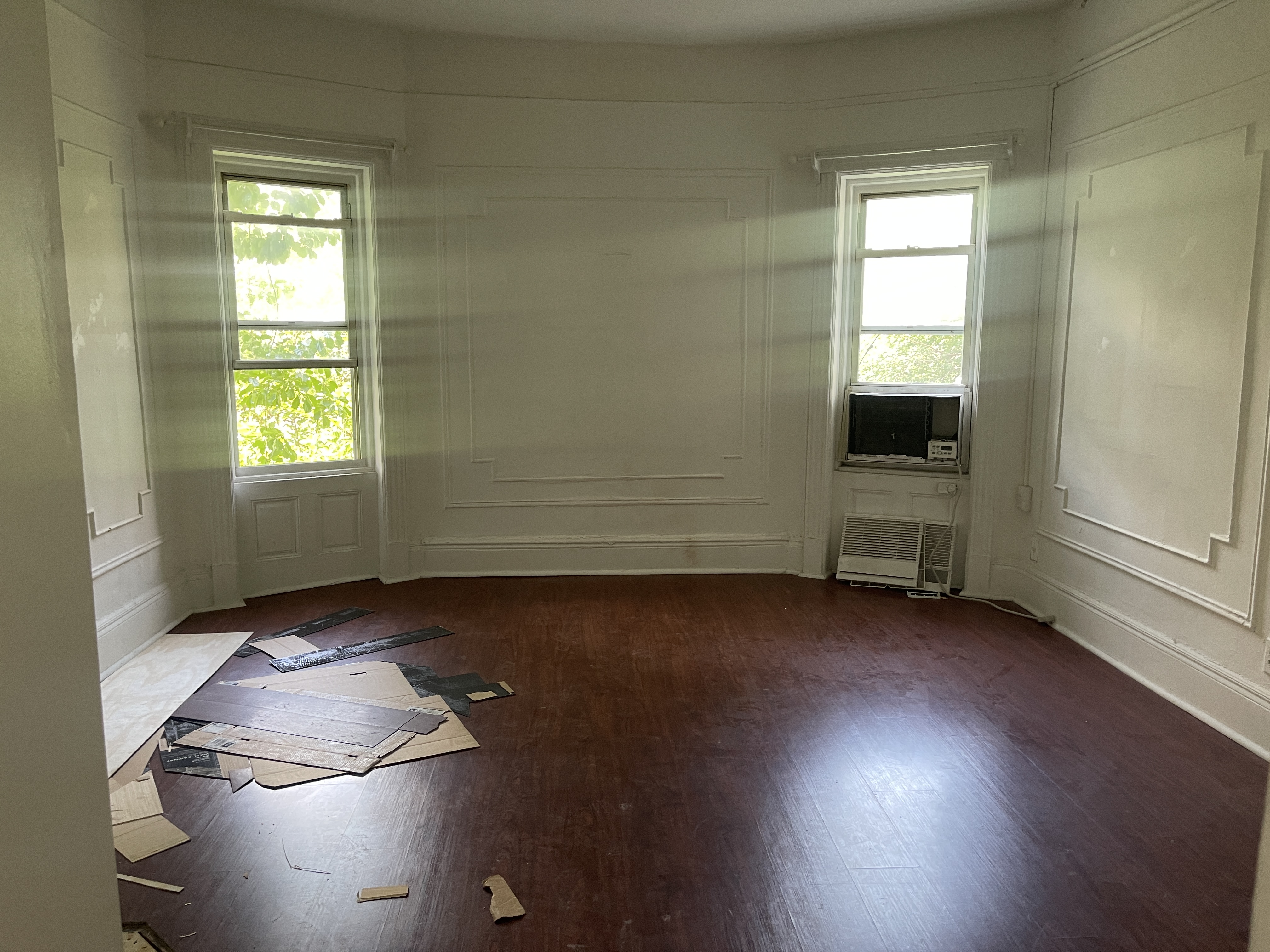 an empty room with wooden floor and windows