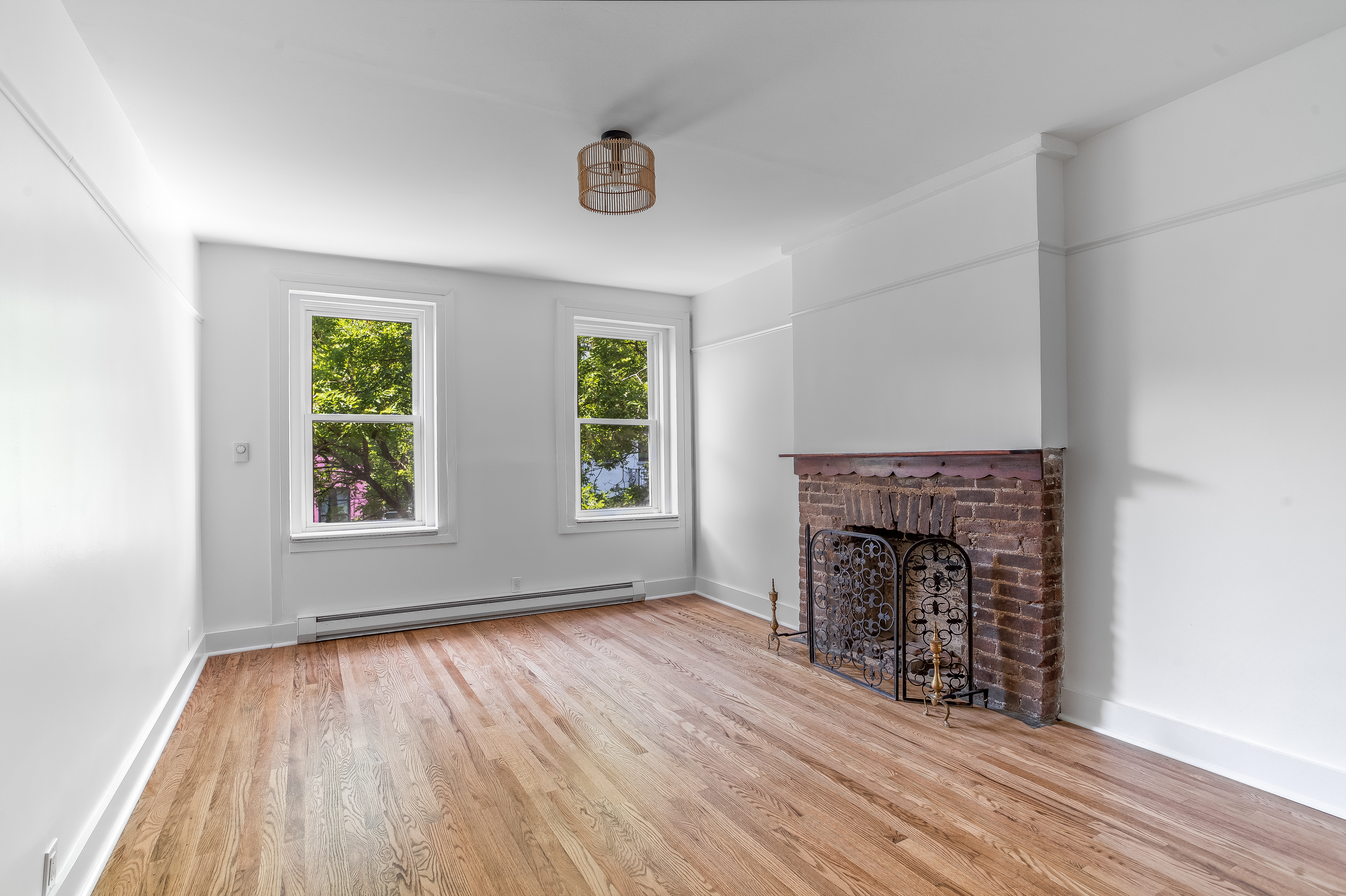 an empty room with windows a fireplace and wooden floor