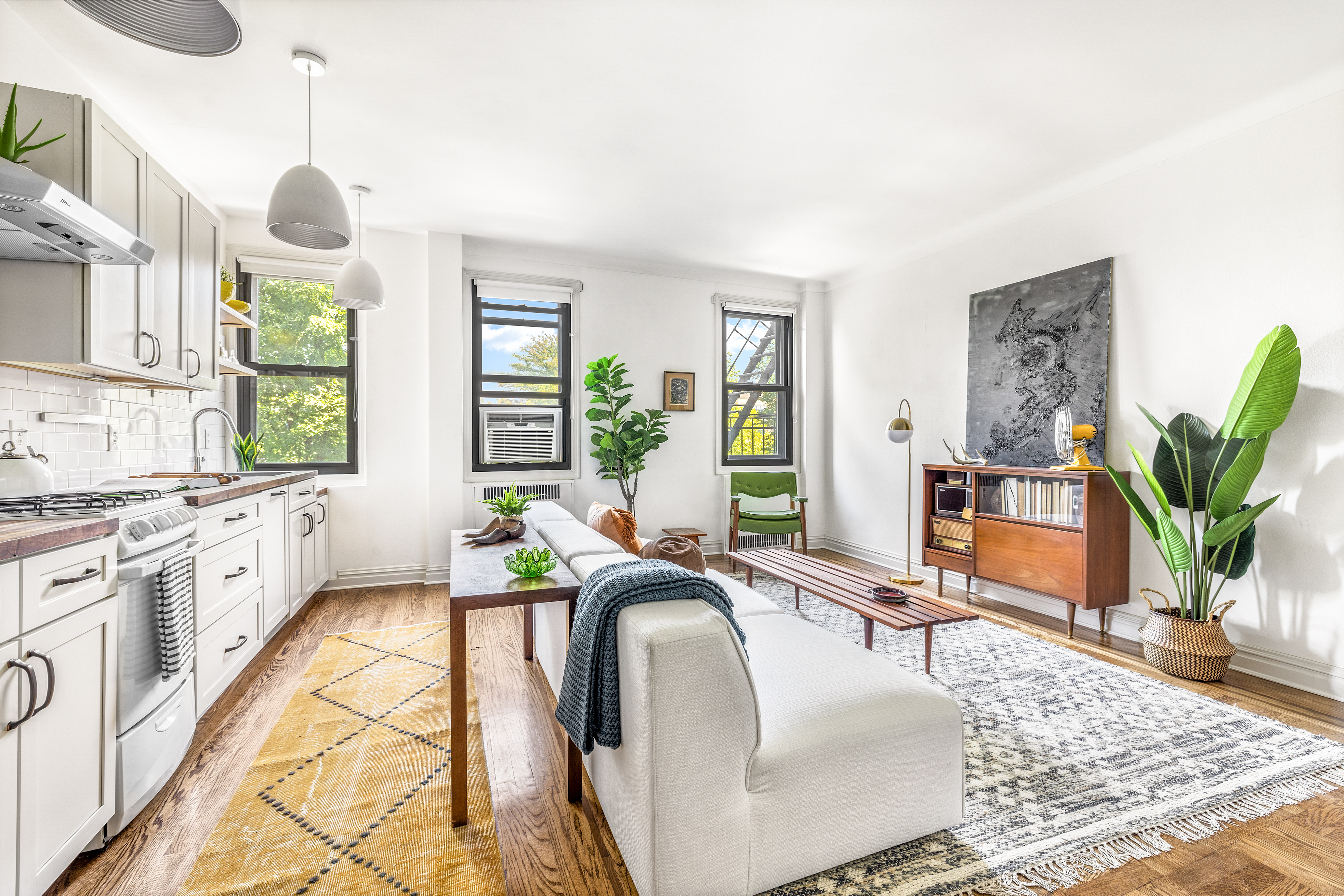 a living room with granite countertop furniture a chandelier a large window and potted plant