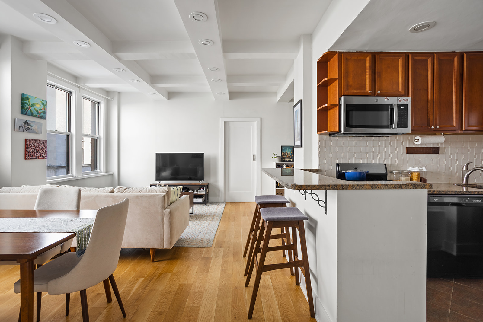 a living room with stainless steel appliances furniture a flat screen tv and a window