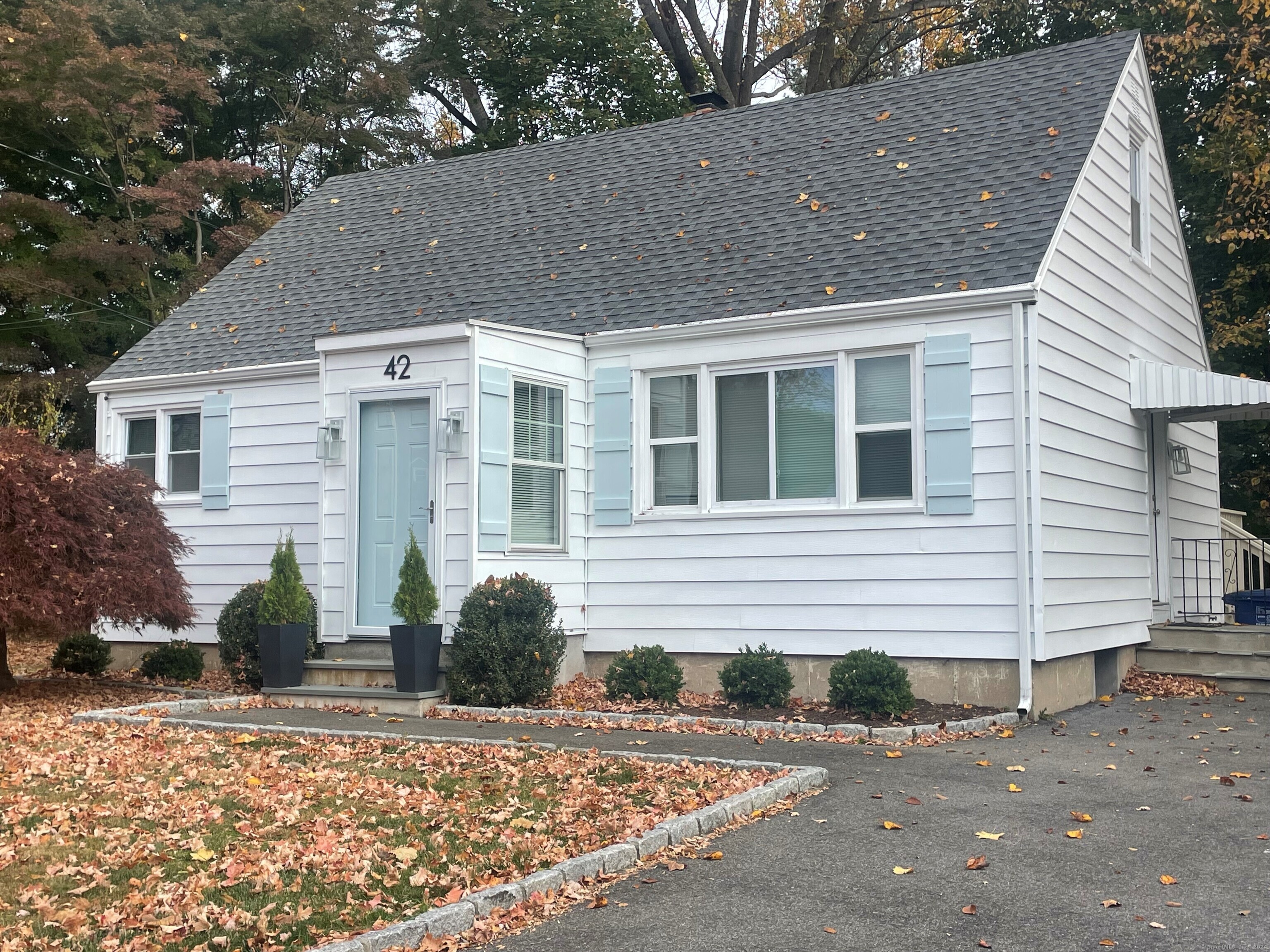 a view of a blue house with a yard and large tree