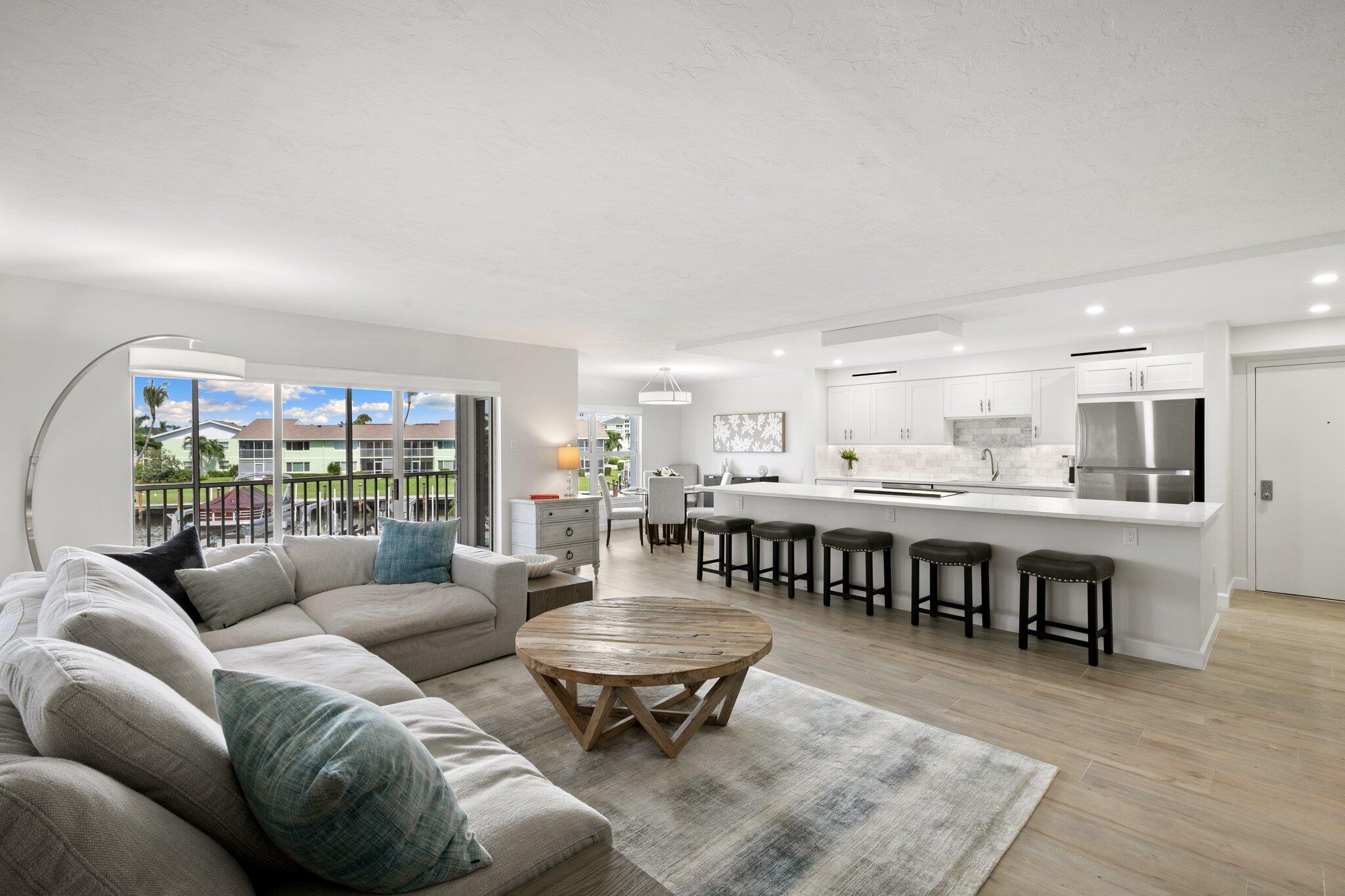 a living room with furniture a table and kitchen view