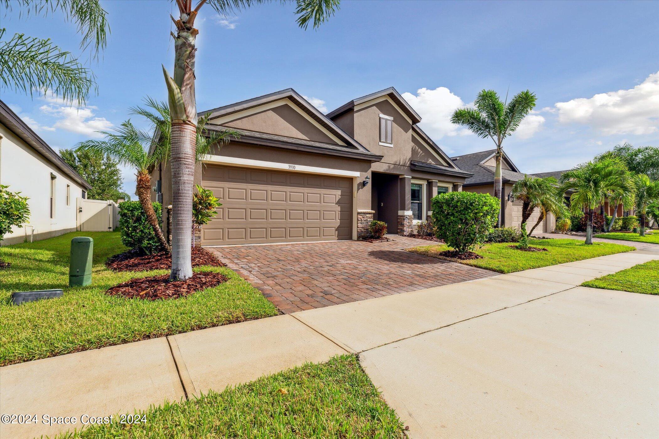 a front view of a house with a yard and potted plants