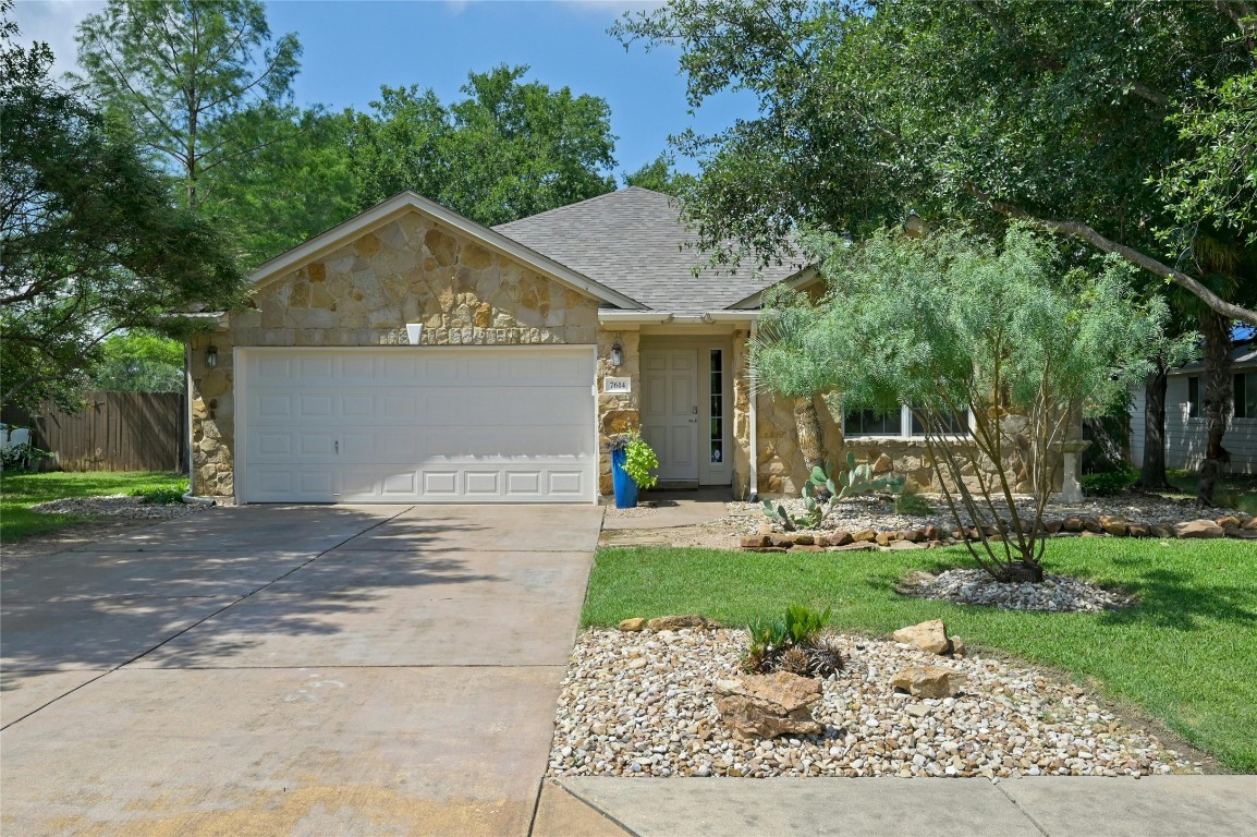 Front of house with gorgeous landscaping and tall trees