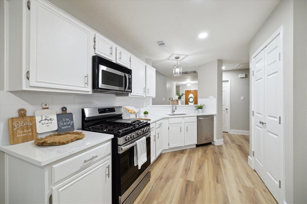 a kitchen with granite countertop a sink a counter top space stainless steel appliances and cabinets