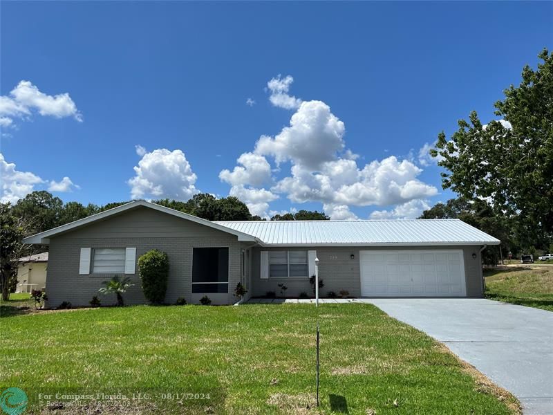 a front view of house with yard and trees in the background