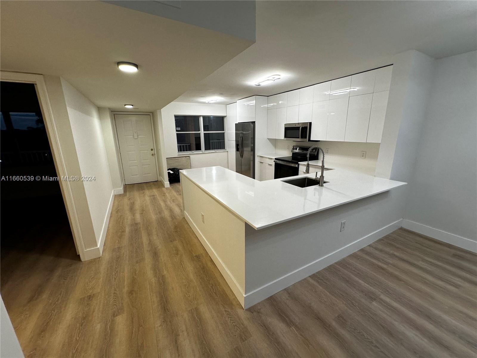 a kitchen view with wooden floor and windows