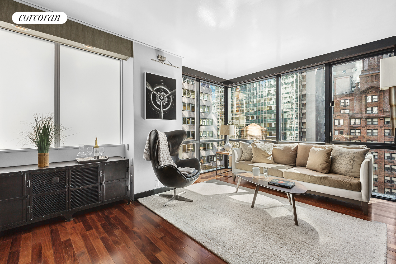 a living room with furniture floor to ceiling window and wooden floor