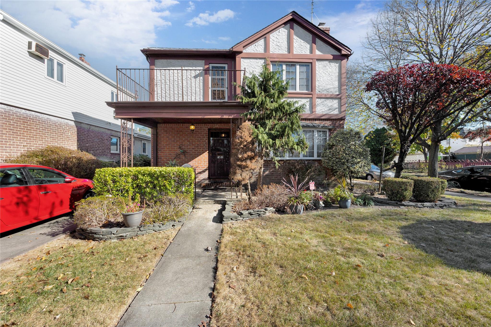 View of front of property featuring a balcony and a front yard