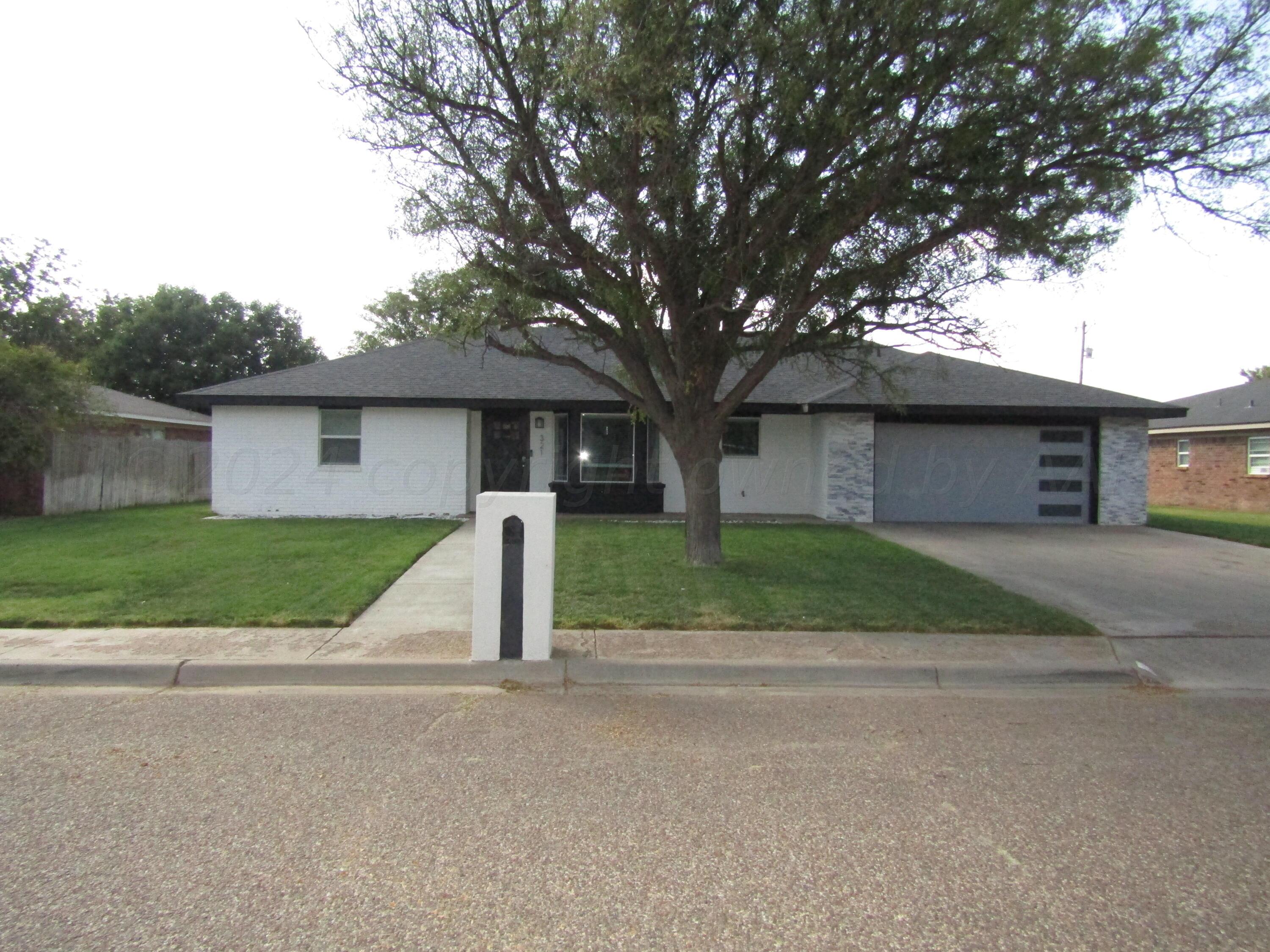 a view of a house with a yard and large tree