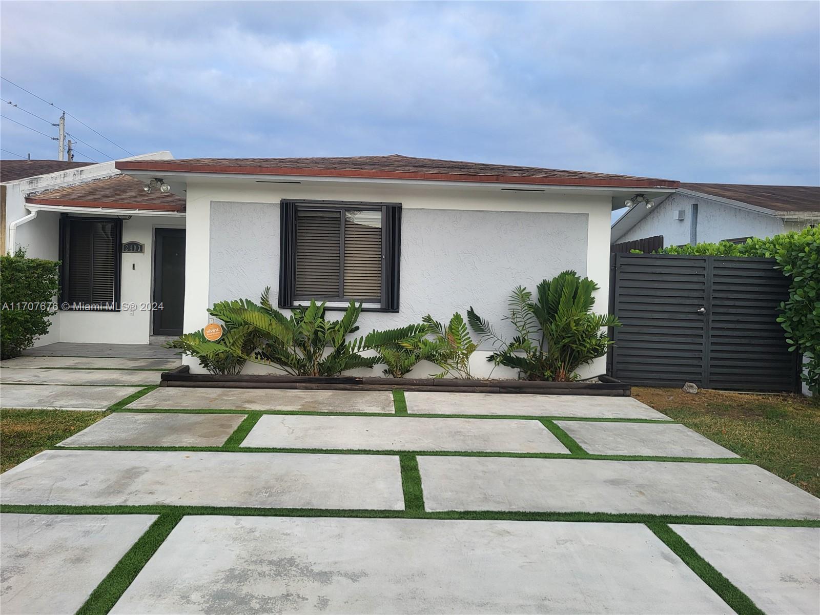 a front view of a house with garage and plants