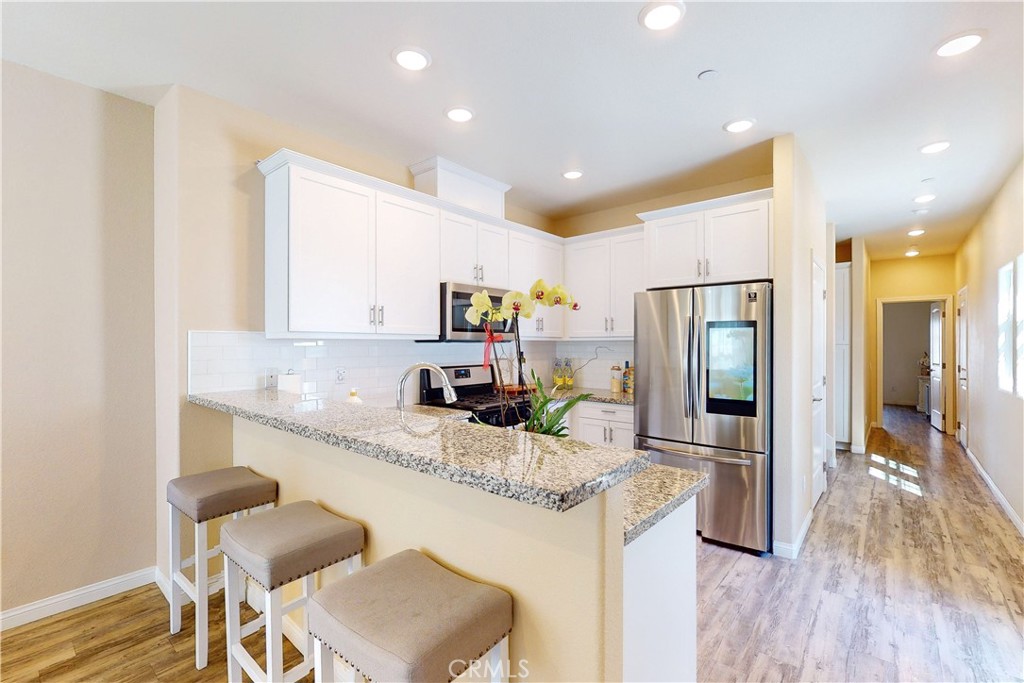 a kitchen with granite countertop kitchen island stainless steel appliances a sink and a refrigerator