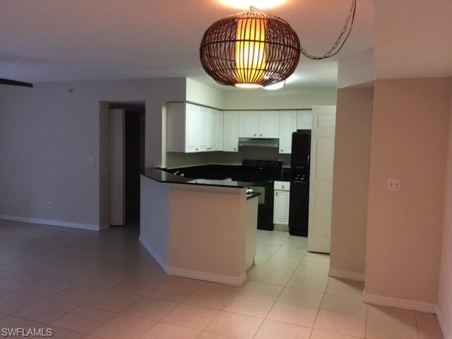 Kitchen featuring ventilation hood, black appliances, white cabinets, light tile patterned floors, and kitchen peninsula