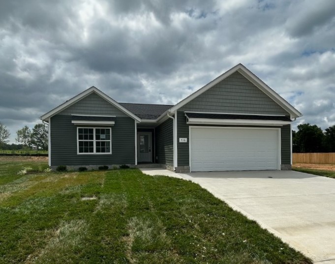 a front view of a house with yard and trees in the background