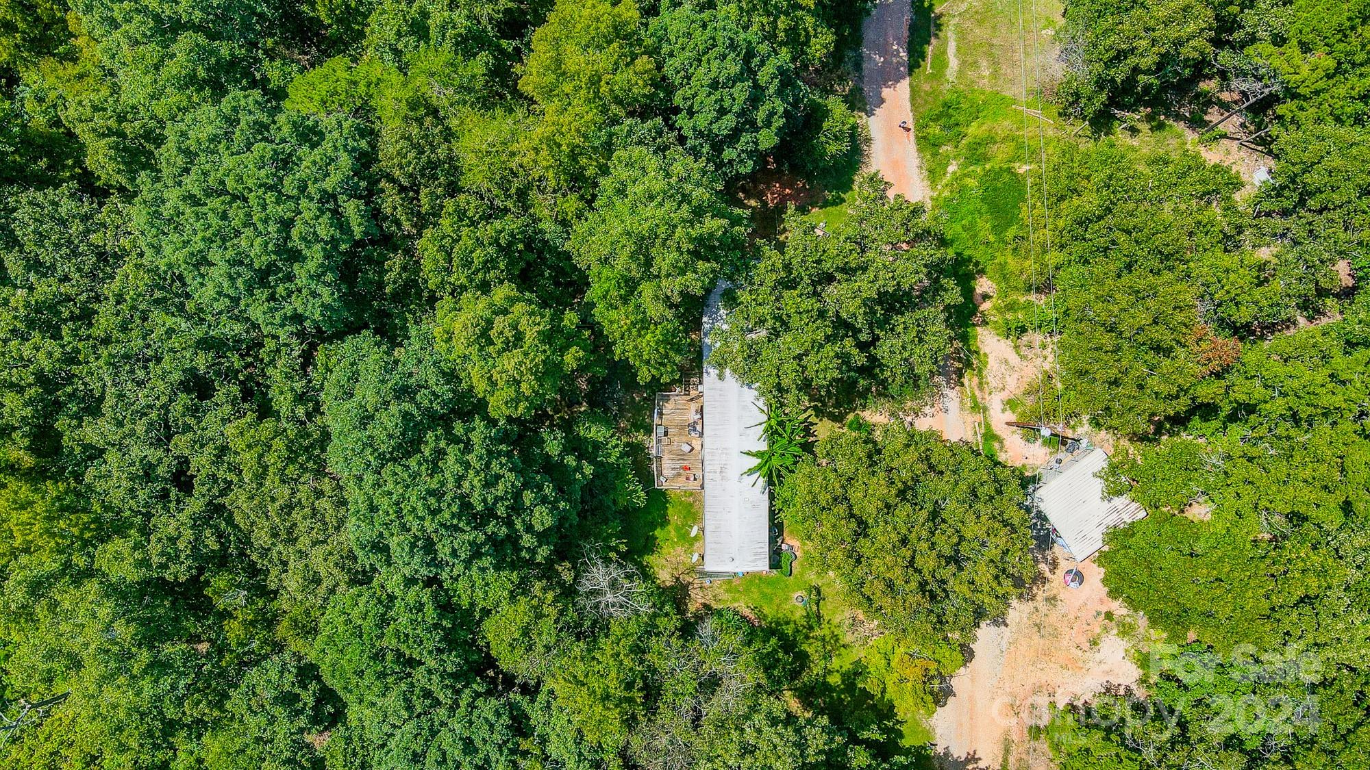 an aerial view of residential house with outdoor space and trees all around