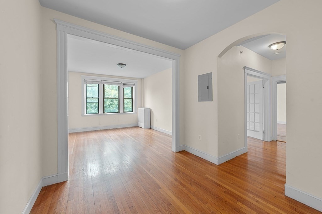 a view of an empty room with wooden floor and a window