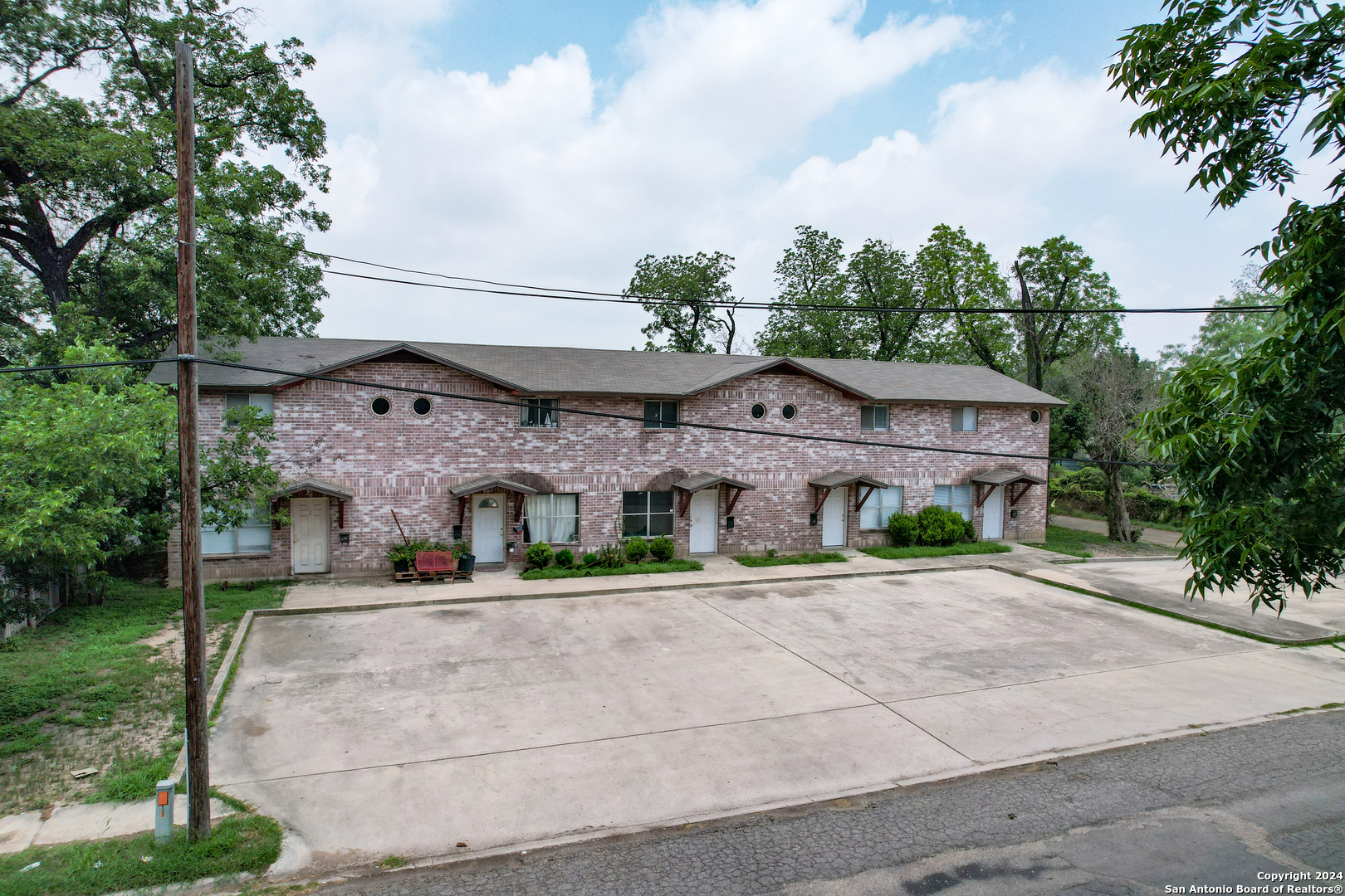 a view of a brick house next to a yard with big trees