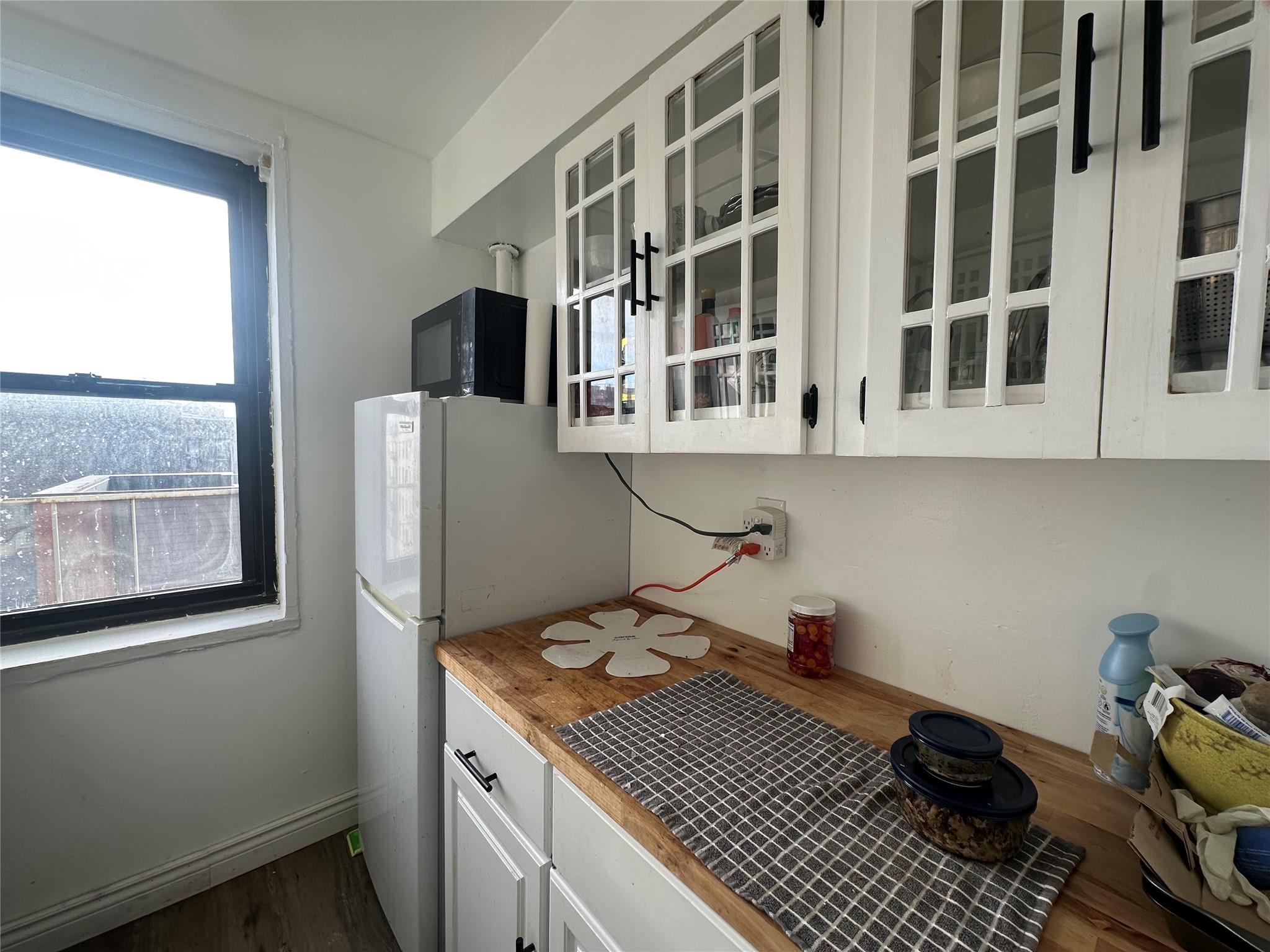 Kitchen featuring white refrigerator, dark hardwood / wood-style flooring, and white cabinetry