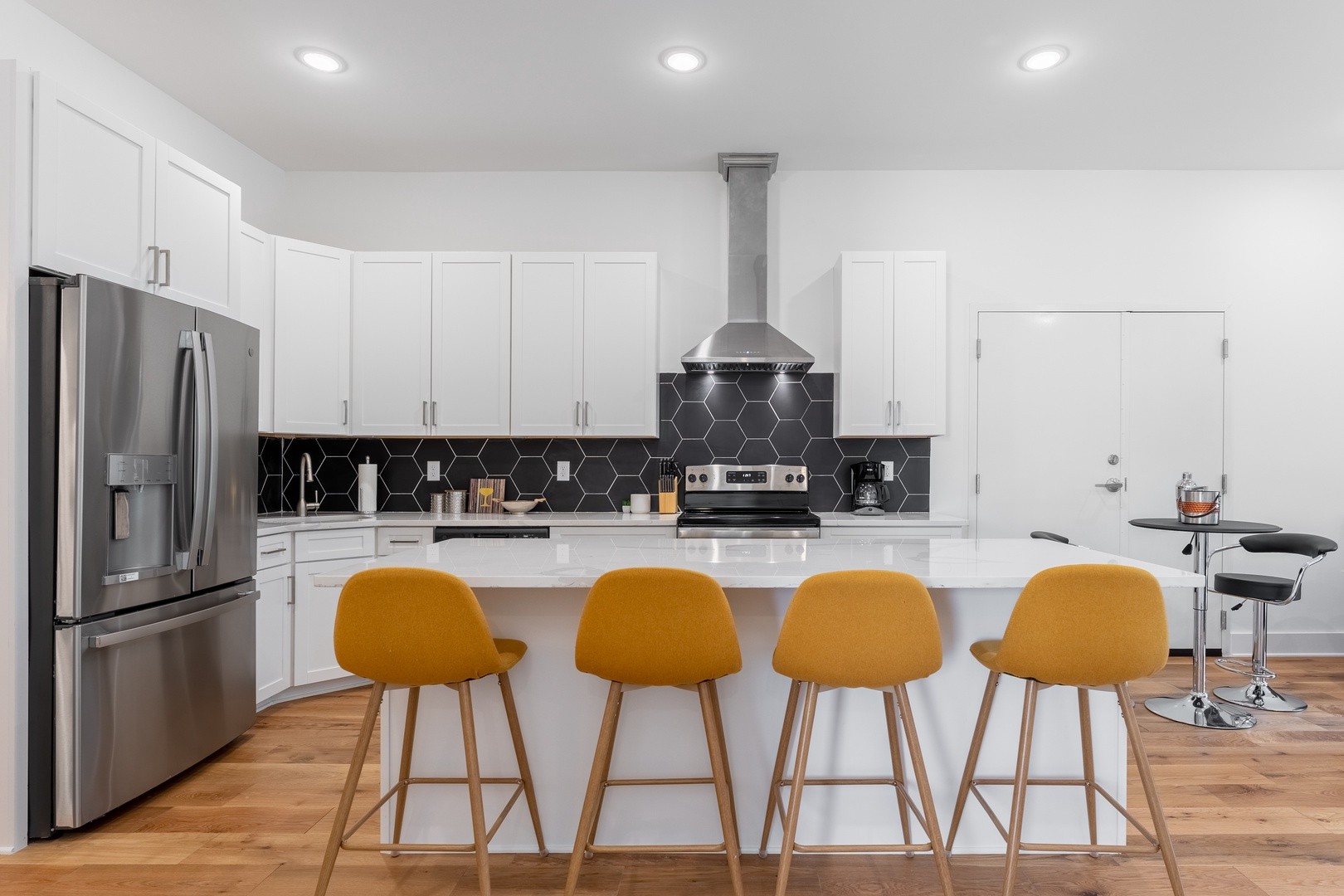 a kitchen with stainless steel appliances a dining table chairs refrigerator and sink