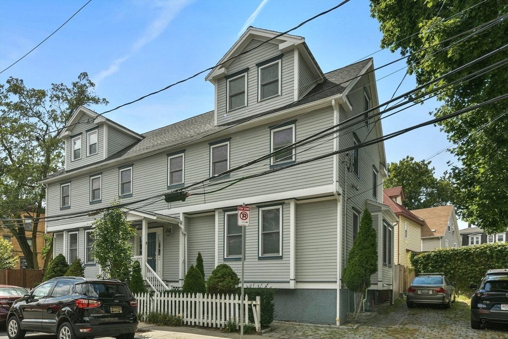 a view of a house with a cars park side of a road