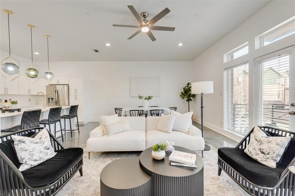 a living room with furniture kitchen view and a large window