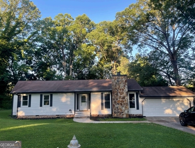 a front view of a house with a garden and trees