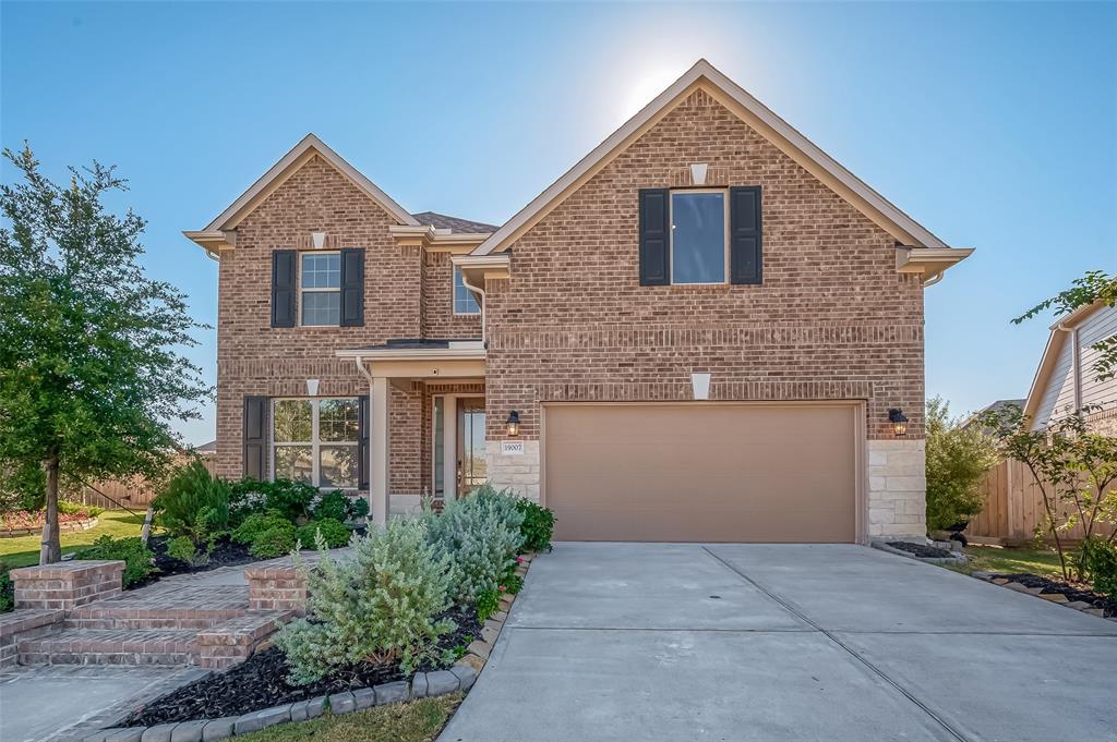 Two-story brick home featuring a well-maintained front yard with landscaping and two-car attached garage. The house has a welcoming entryway and a combination of large and accent windows for natural light. Welcome to your new home - 19007 Yellowstone Landing Ct.