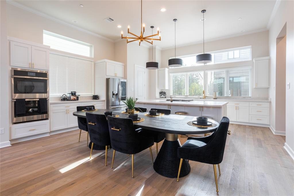 a room with stainless steel appliances kitchen island granite countertop a table chairs and a wooden floor