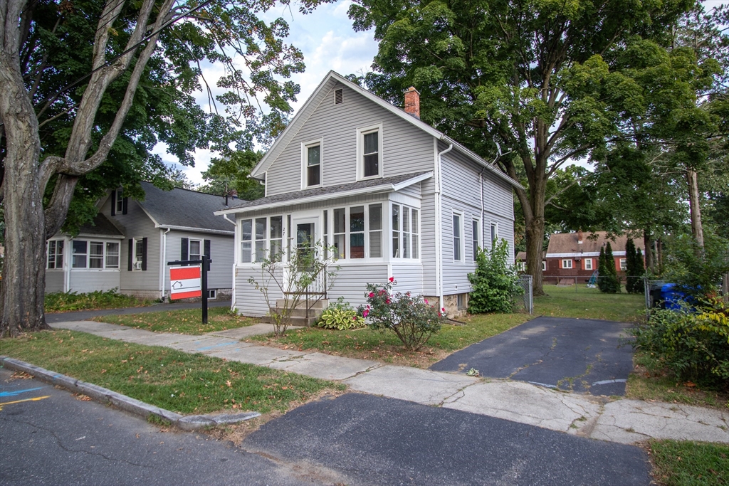 a front view of a house with a garden and trees