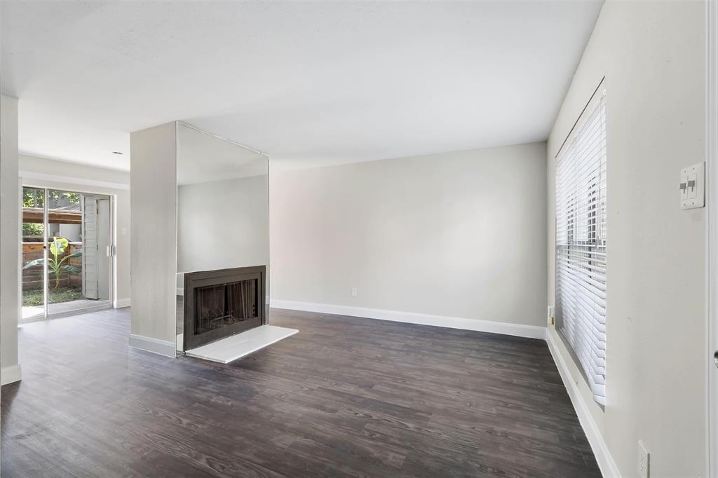 an empty room with windows fireplace and wooden floor