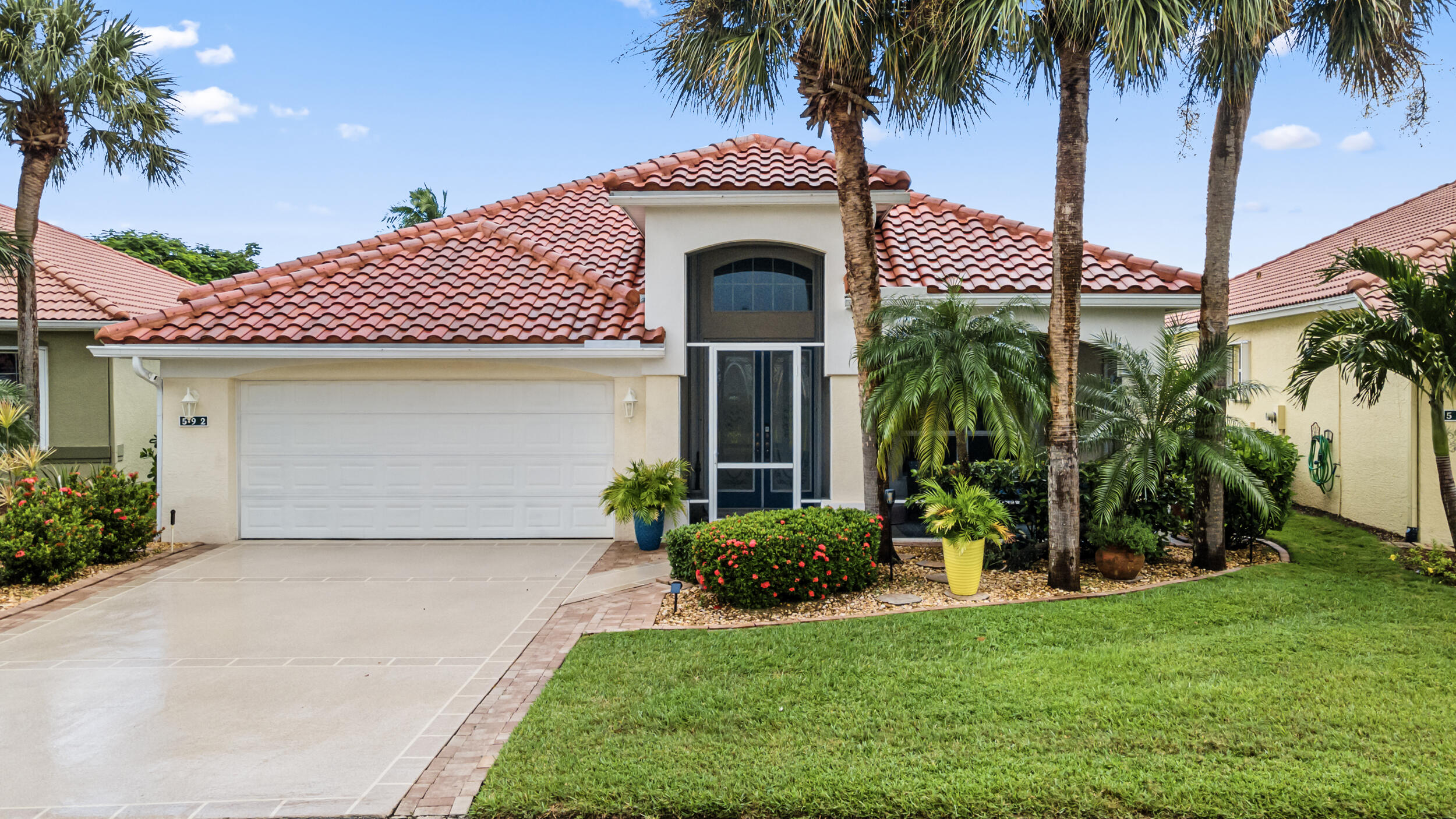 a front view of a house with a garden and palm trees