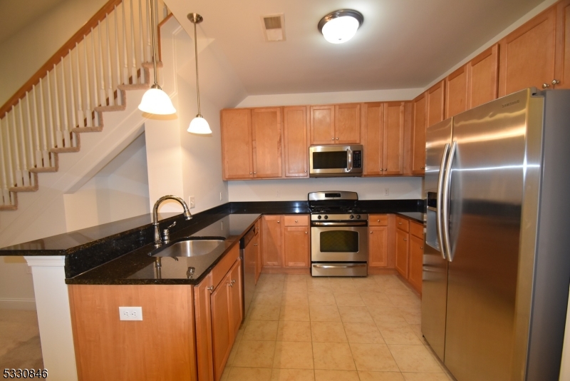 a kitchen with stainless steel appliances granite countertop a sink a stove and a refrigerator