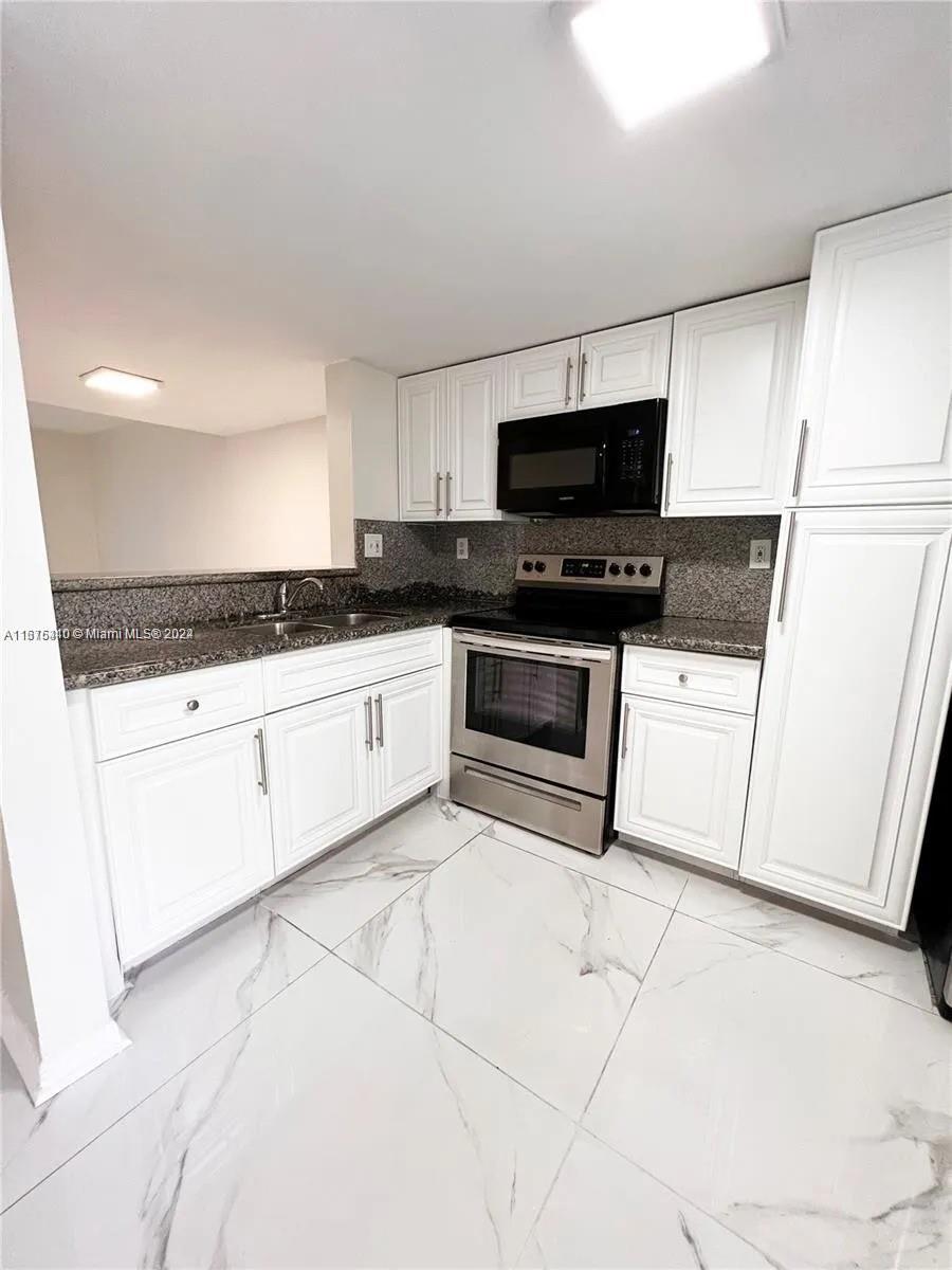 a kitchen with granite countertop white cabinets and white appliances