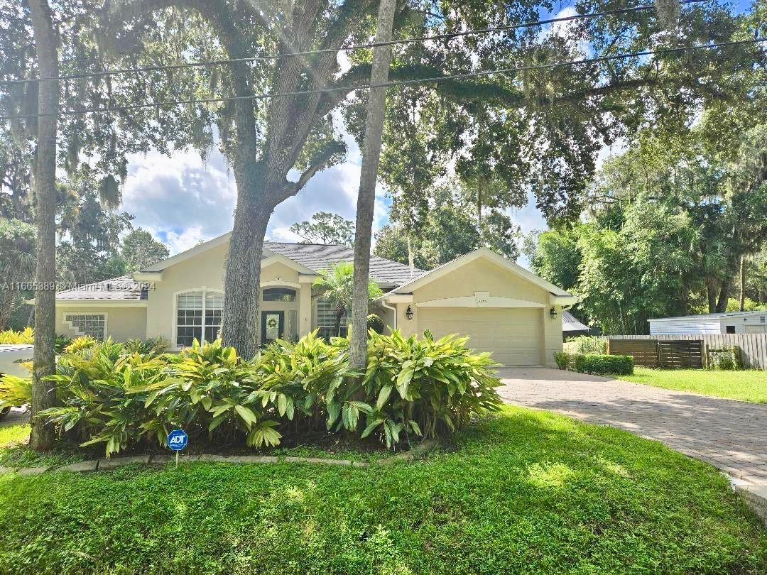 a front view of a house with a garden and trees