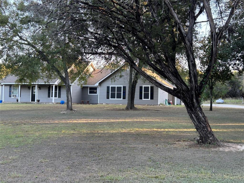 a front view of a house with a yard and large trees