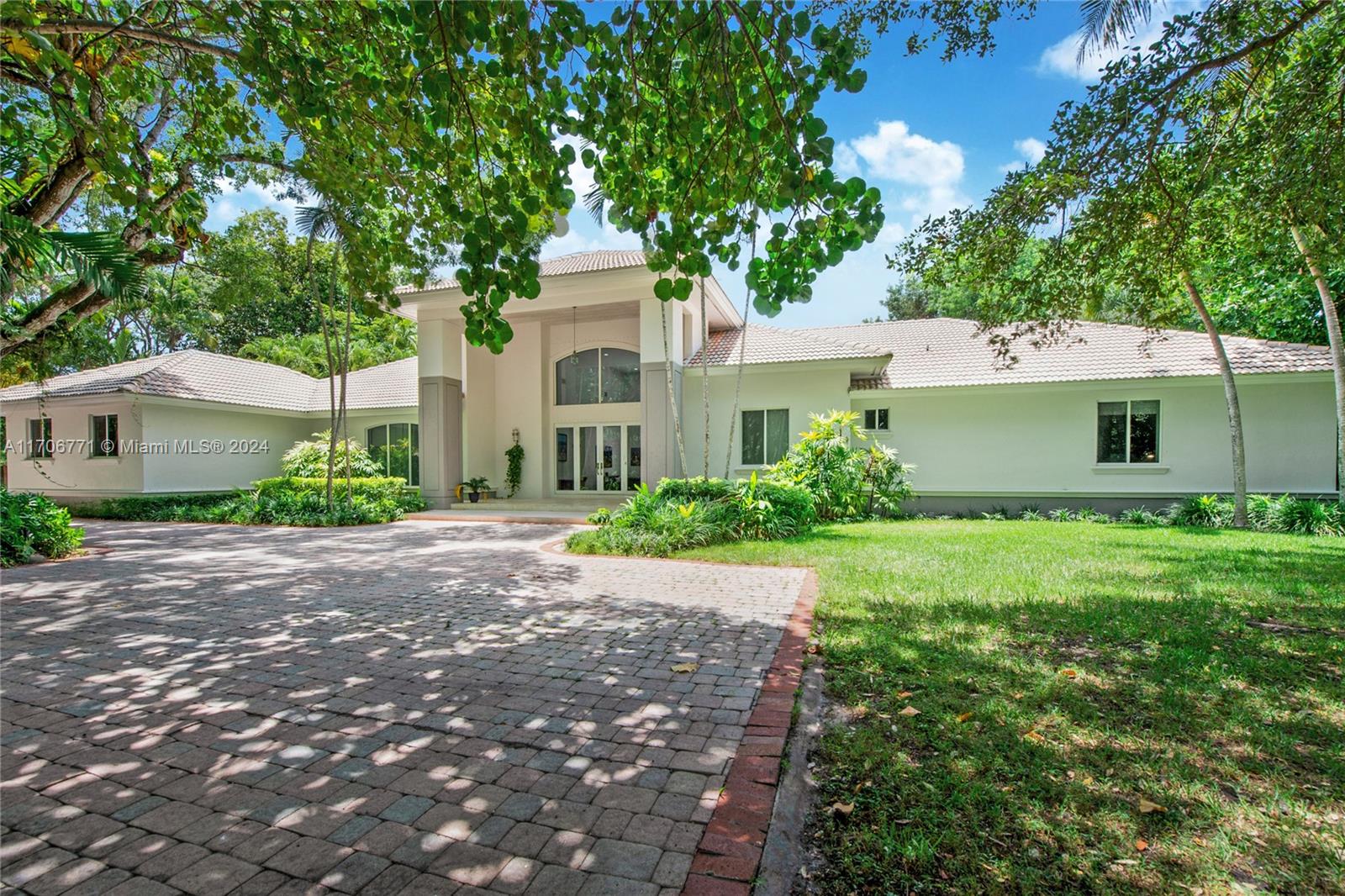 a front view of a house with a garden and trees