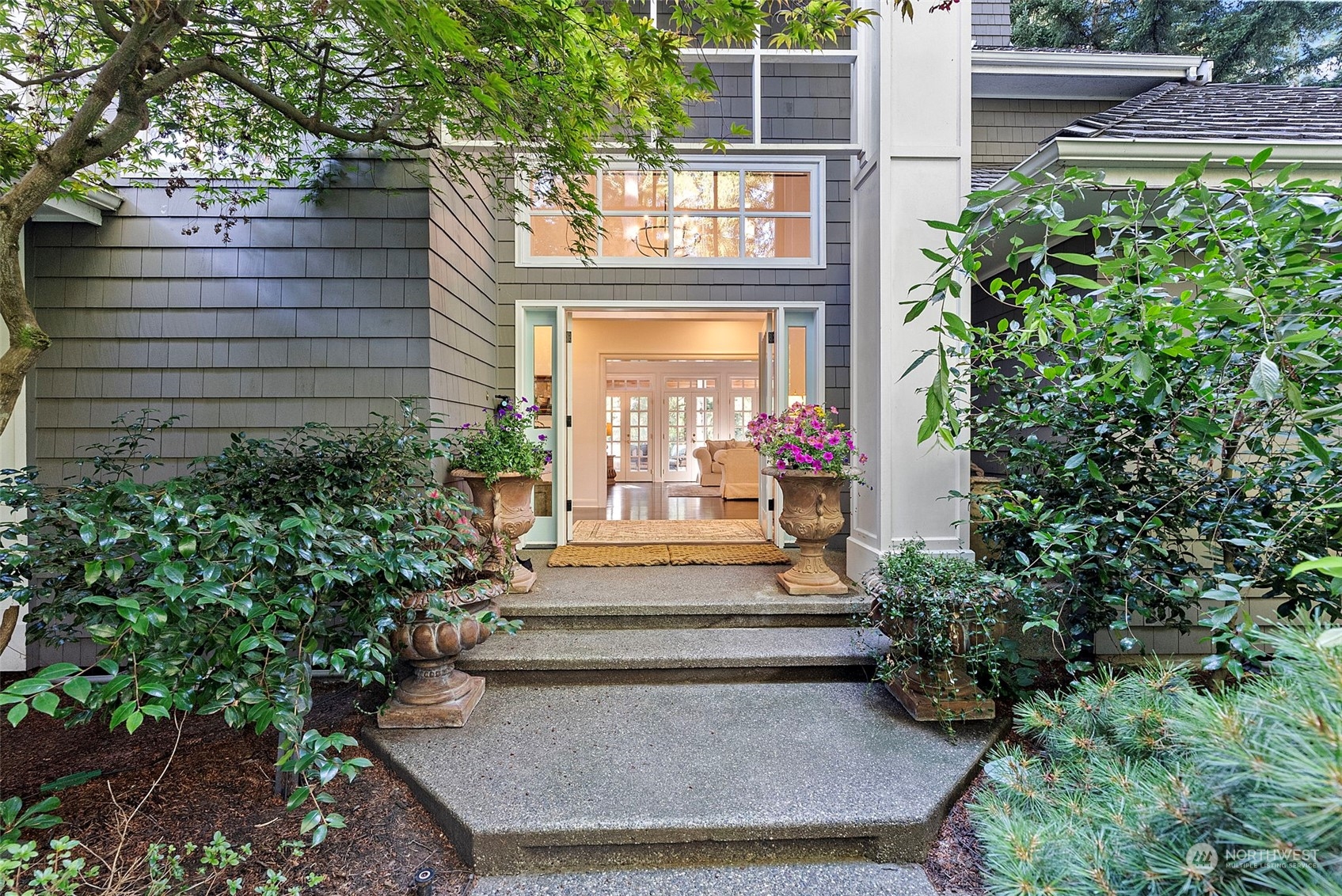 a view of a house with a small yard plants and large tree