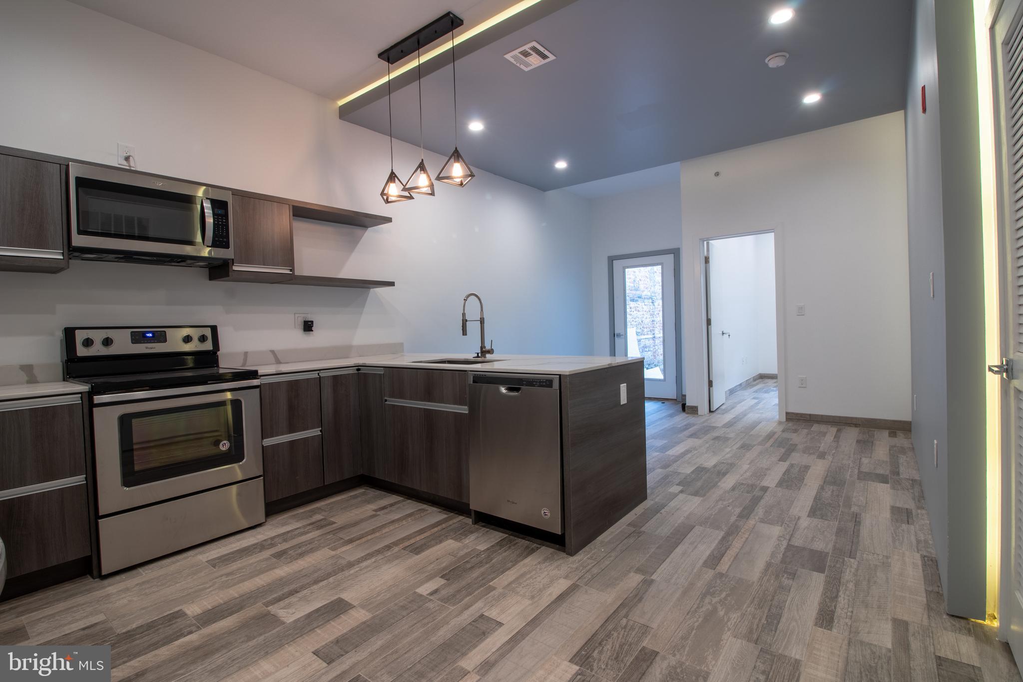 a kitchen with stainless steel appliances granite countertop a sink a stove top oven and wooden floors