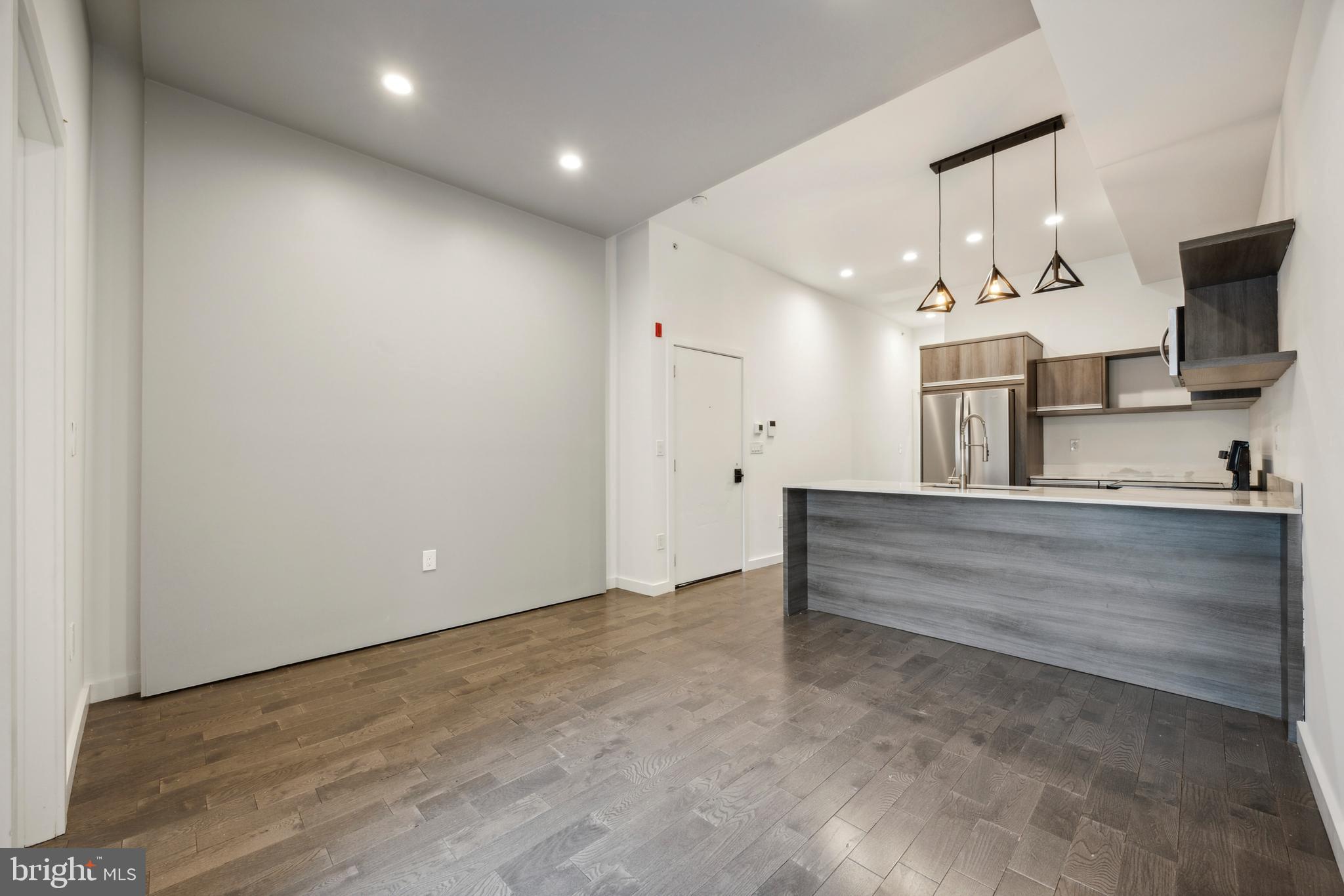 a view of living room kitchen with stainless steel appliances cabinets