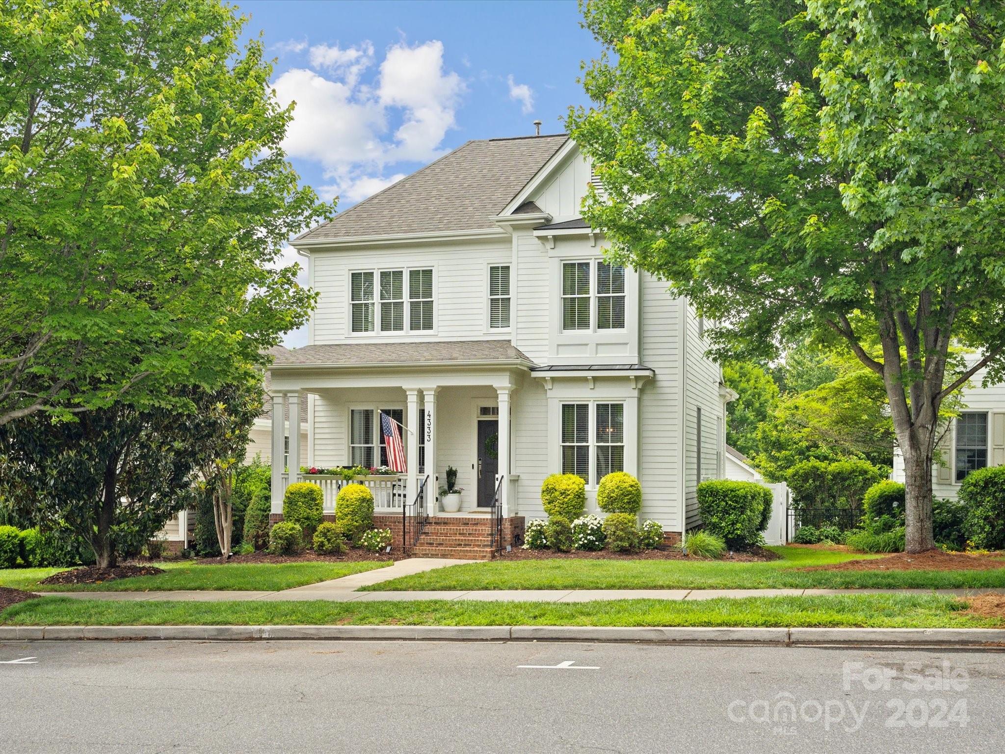 a front view of a house with a garden and trees