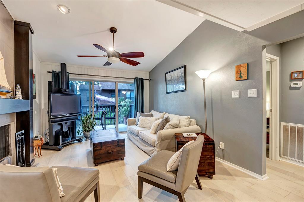 This cozy living room features neutral decor, a ceiling fan, and a sliding glass door leading to a patio.